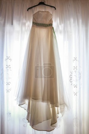 Téléchargez les photos : Robe de mariée suspendue à un cintre dans une chambre - en image libre de droit
