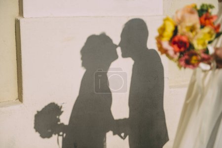 Foto de Silueta de novia y novio sosteniendo un ramo y besándose - Imagen libre de derechos