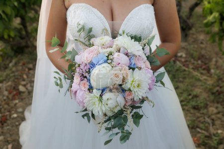 Téléchargez les photos : Belle mariée dans une robe de mariée tenant un bouquet de fleurs de mariage. le concept de mariage. - en image libre de droit