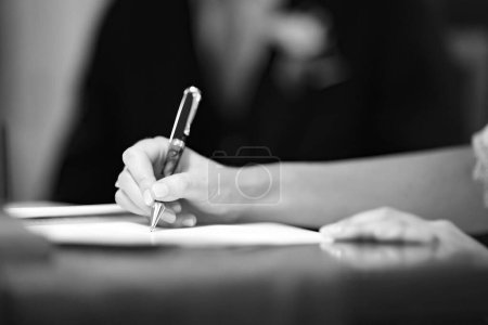 Téléchargez les photos : Un gros plan de la main d'une femme signant un document - en image libre de droit