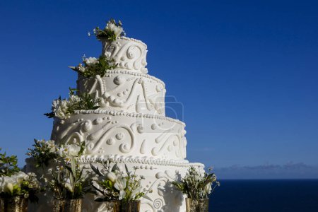 Foto de Pastel de boda blanco con flores en la costa del mar - Imagen libre de derechos