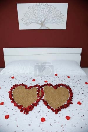 Photo for Beautiful red rose petals and grains decorated on a honeymoon bed for couples - Royalty Free Image