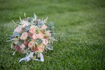 Photo for Wedding bouquet with white roses and ribbons on grass. - Royalty Free Image
