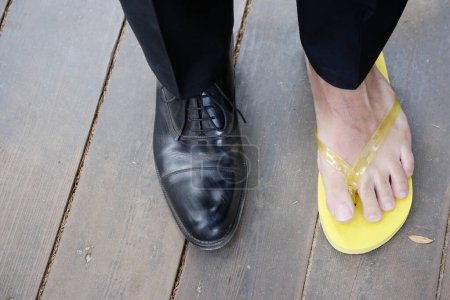 Foto de Tiro recortado de las piernas del hombre en chancla y zapato elegante - Imagen libre de derechos