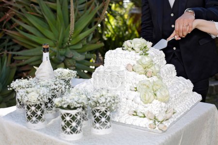 Téléchargez les photos : Fermer - vers le haut des alliances sur la table dans le gâteau de mariage blanc et les roses. gâteau de mariage sur la table - en image libre de droit