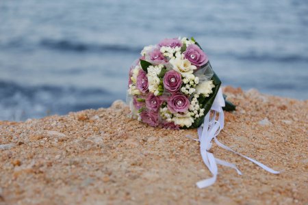 Téléchargez les photos : Un gros plan de beau bouquet de fleurs avec des alliances dans une plage de sable fin sur un rivage sablonneux - en image libre de droit