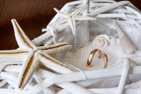Foto de Conchas de mar, estrellas de mar y anillos de boda en una cesta blanca - Imagen libre de derechos