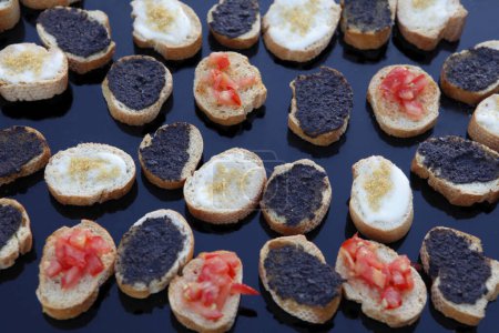 Foto de Canapé con caviar negro y aceitunas sobre una mesa de madera - Imagen libre de derechos