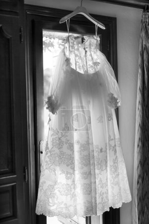 Téléchargez les photos : Belle robe de mariée avec un cintre accroché dans la chambre - en image libre de droit