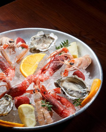 Téléchargez les photos : Gros plan de fruits de mer, huîtres crues fraîches, crevettes et citron sur glace - en image libre de droit