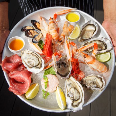Téléchargez les photos : Gros plan de poissons et fruits de mer crus frais dans l'assiette avec citron et ail - en image libre de droit