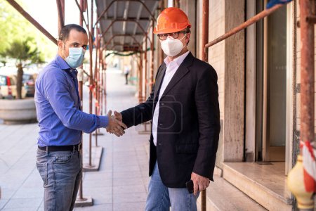 Photo for Two male architects in face masks shaking hands - Royalty Free Image