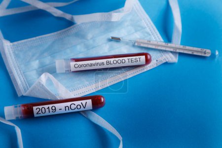 Téléchargez les photos : Éprouvettes de sang, thermomètre et autres articles liés au coronavirus, isolées sur fond bleu - en image libre de droit