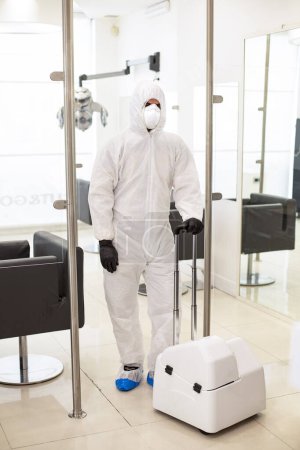 Photo for Technician for the disinfestation of premises ready to use the specific machine to sanitize a hair salon - Royalty Free Image