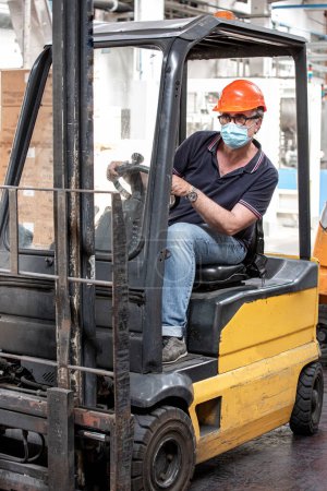 Téléchargez les photos : Travailleur dans l'usine avec chariot élévateur et équipement - en image libre de droit
