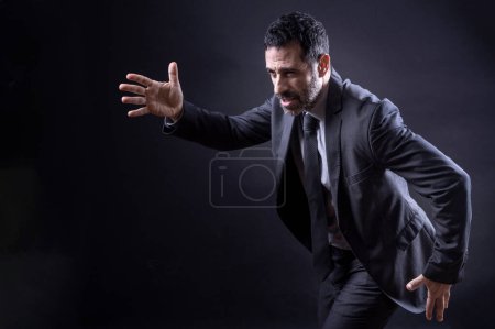 Photo for Manager in elegant suit runs quickly isolated on black background - Royalty Free Image