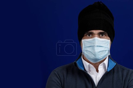 Téléchargez les photos : Portrait d'homme avec masque de protection et capot, isolé sur fond bleu - en image libre de droit