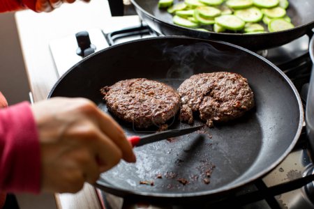 Photo for Hamburgers on pan in cooking and next to the other pan with zucchiene - Royalty Free Image