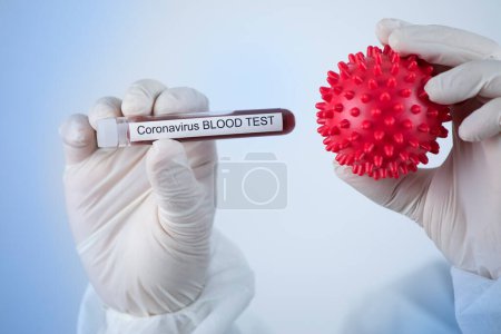 Photo for Doctor is holding the symbol of the coronavirus which is a red ball - Royalty Free Image