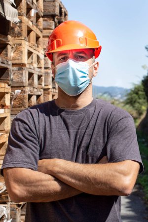 Foto de Trabajador con casco protector inmerso en paletas apiladas - Imagen libre de derechos