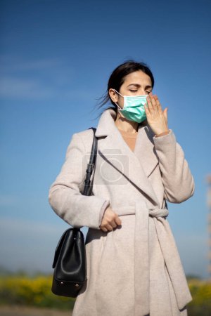Photo for Girl with you coat and face mask brings her hands near her mouth - Royalty Free Image