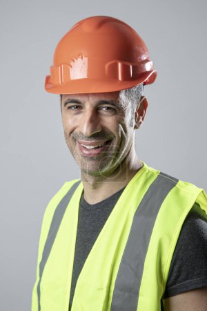 Téléchargez les photos : Portrait travailleur brun avec casque et gilet jaune, isolé sur fond clair - en image libre de droit