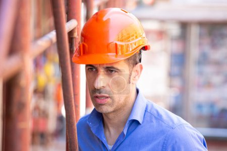 Téléchargez les photos : Ingénieur avec casque orange orange et chemise bleue dans le cadre d'un chantier urbain - en image libre de droit