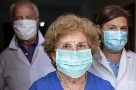 Téléchargez les photos : Portrait rapproché de médecins chevronnés portant des masques de protection médicale - en image libre de droit