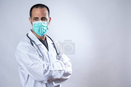 Foto de Médico con máscara quirúrgica y bata blanca aislada sobre fondo blanco - Imagen libre de derechos