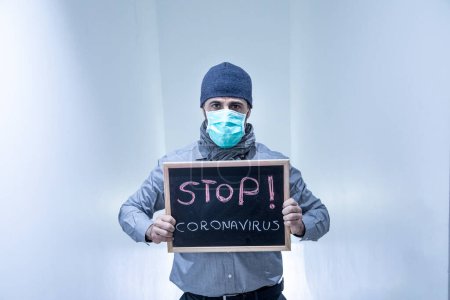Foto de Hombre de pelo oscuro en traje con una máscara antivirus, muestra un signo contra la corona del virus - Imagen libre de derechos