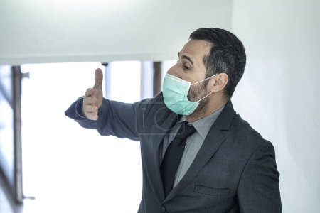 Foto de Empresario en traje con una máscara antivirus, cae dentro de su estudio profesional - Imagen libre de derechos