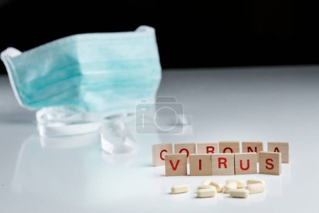 Téléchargez les photos : Écrit "virus corona" avec des lettres en bois avec masque de protection, isolé sur fond noir - en image libre de droit