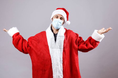 Téléchargez les photos : Père Noël avec masque chirurgical lève les bras vers le ciel, isolé sur fond blanc - en image libre de droit