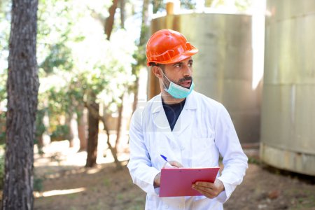 Photo for Technician with white coat, protective helmet and surgical mask in industrial context - Royalty Free Image