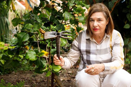Téléchargez les photos : Femme âgée au jardin à la maison - en image libre de droit