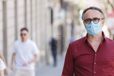 Téléchargez les photos : Homme avec amarante chemise de couleur, masque facial et lunettes noires en zone urbaine - en image libre de droit