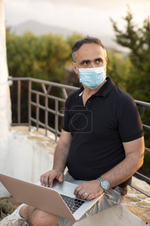 Photo for Man on vacation dressed casual relaxes in a seaside resort protected by the facial mask - Royalty Free Image