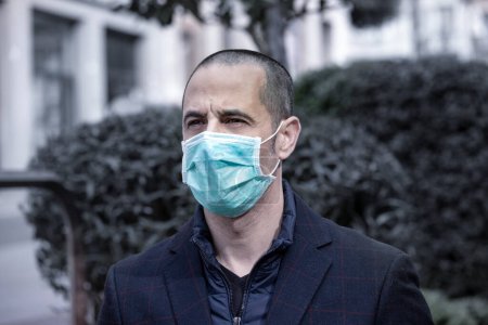 Téléchargez les photos : Portrait homme veste à carreaux bleu, inquiet, avec masque antivirus, dans la ville - en image libre de droit