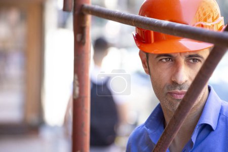 Téléchargez les photos : Ingénieur avec casque orange orange et chemise bleue dans le cadre d'un chantier urbain - en image libre de droit