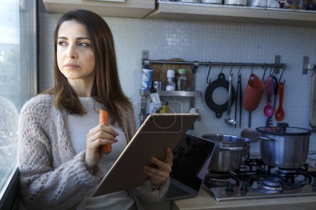 Foto de Chica en la cocina trabaja con su tableta mientras cocina - Imagen libre de derechos