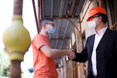 Téléchargez les photos : Deux hommes avec des masques faciaux en usine - en image libre de droit