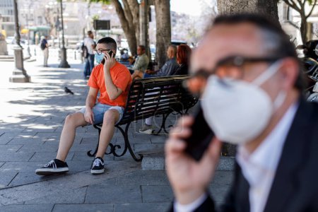 Téléchargez les photos : Hommes en masques de protection avec téléphones mobiles dans la rue - en image libre de droit