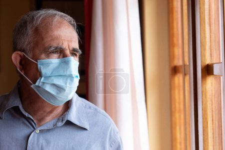 Téléchargez les photos : Portrait d'un homme âgé avec masque à l'intérieur de sa maison - en image libre de droit