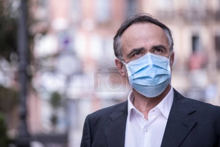 Photo for Man dressed in suit with protective face mask in urban context - Royalty Free Image