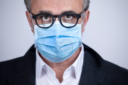 Téléchargez les photos : Portrait d'homme portant un masque chirurgical, veste et chemise, isolé sur fond - en image libre de droit