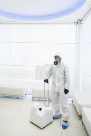 Foto de Técnico con respirador protector y mono blanco listo para la desinfección antivirus y antibacteriana en un local - Imagen libre de derechos