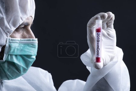 Photo for Doctor in protective suit and mask is holding tube for coronavirus blood test - black background - Royalty Free Image