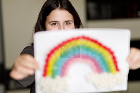 Photo for Brunette girl with black shirt shows a drawing with the rainbow - Royalty Free Image