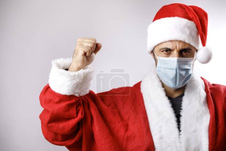 Foto de Santa Claus con máscara quirúrgica levanta los puños hacia el cielo, aislado sobre fondo blanco - Imagen libre de derechos