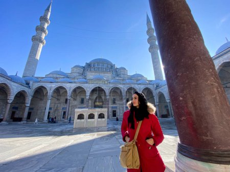 Photo for Woman in red coat walks past a beautiful mosque in Istanbul - Royalty Free Image